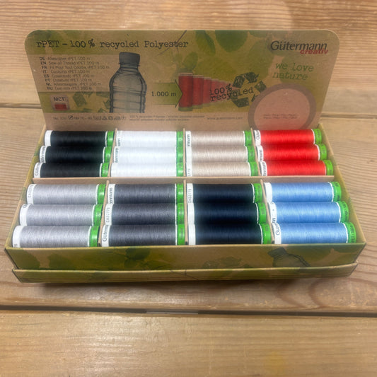 Box of Gutermann recycled polyester thread spools on a wooden surface