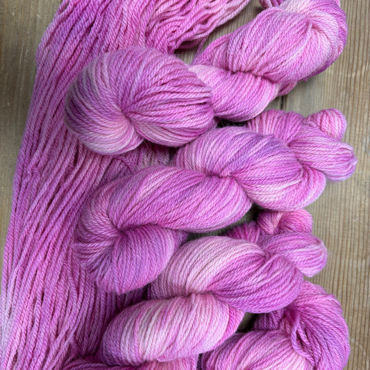 Pink yarn skeins on a wooden surface
