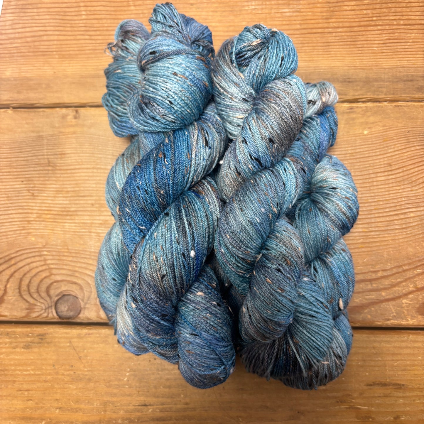 Three skeins of blue yarn on a wooden surface