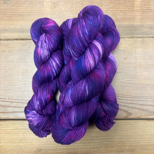 Two skeins of purple yarn on a wooden surface